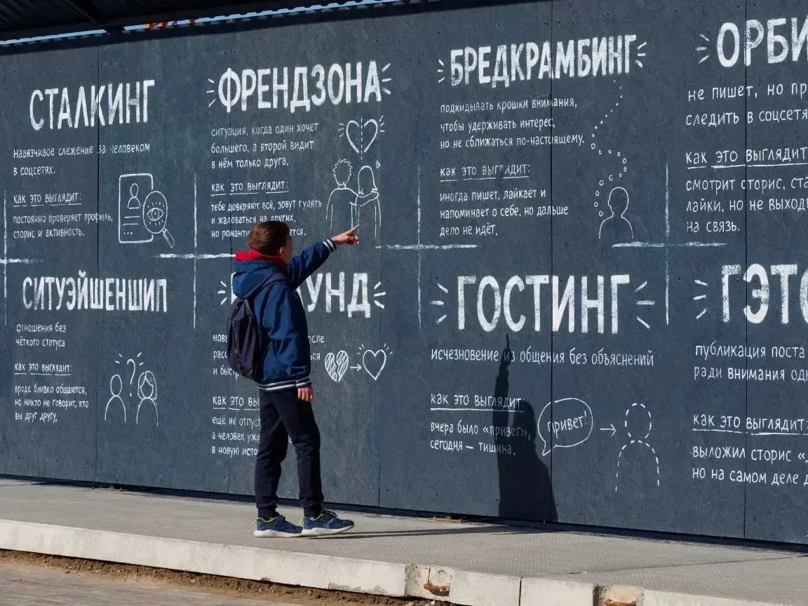 Ограждение строящейся школы на Левом берегу расписали: на заборе объясняют значение эмодзи, популярные сленговые выражения и простыми словами учат понимать друг друга.
