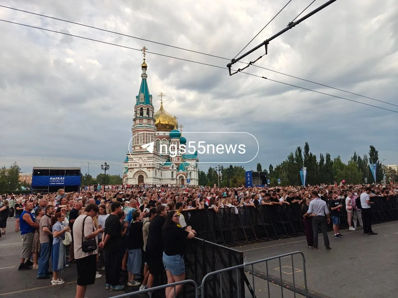 У сцены в Омске уже собираются зрители: через 15 минут начнёт Андрей Державин, затем выйдет Ольга Серябкина. Пока диджей миксует треки, появляются первые плакаты.